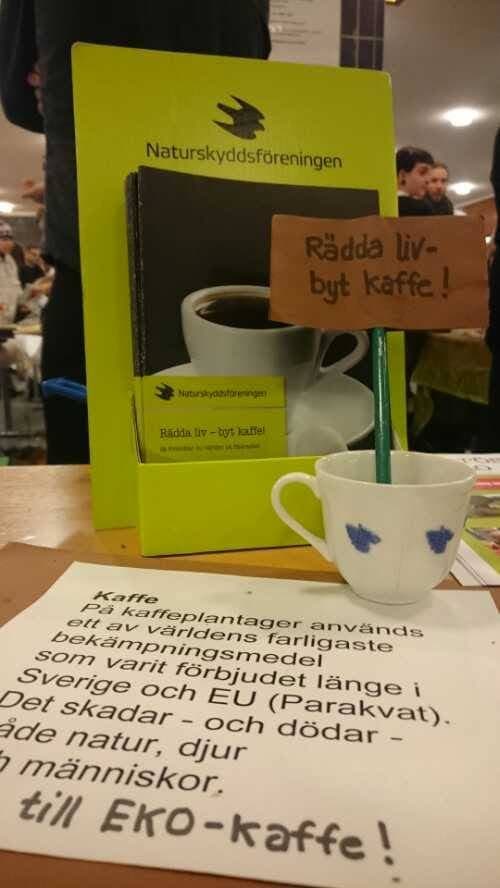 Bild som visar skylt på uppmaning till att byta till miljövänlig kaffe och en kaffekopp
